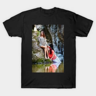Two beautiful young women leaning on rocks beside a river T-Shirt
